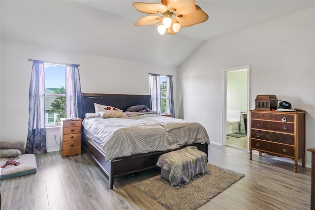 bedroom featuring wood-type flooring, vaulted ceiling, ceiling fan, and connected bathroom