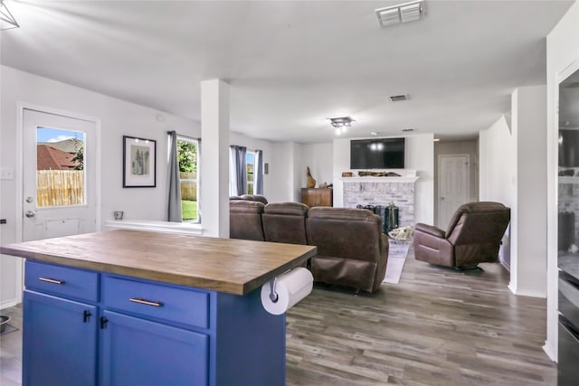 kitchen featuring a kitchen island, butcher block countertops, blue cabinetry, and dark hardwood / wood-style flooring