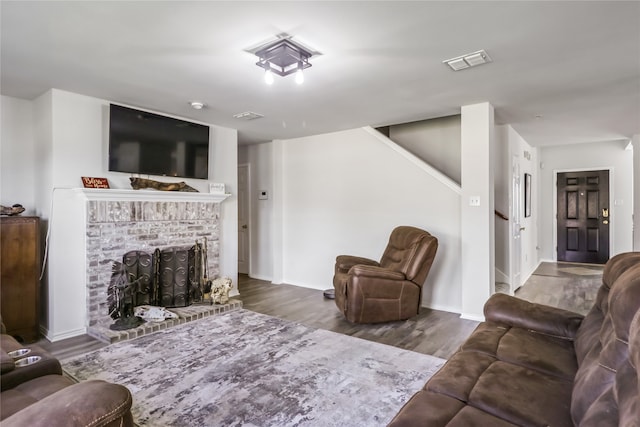 living room featuring a brick fireplace and wood-type flooring