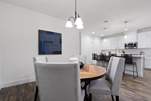 dining area featuring dark wood-type flooring and a chandelier