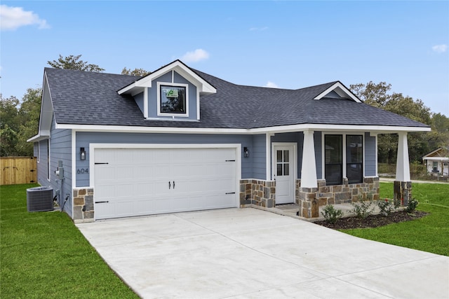 view of front of home featuring central AC unit, a garage, covered porch, and a front lawn