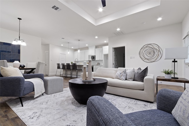 living room featuring a chandelier, sink, and light hardwood / wood-style flooring