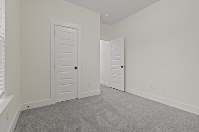 unfurnished bedroom featuring a closet and light colored carpet