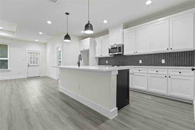 kitchen featuring white cabinets and an island with sink