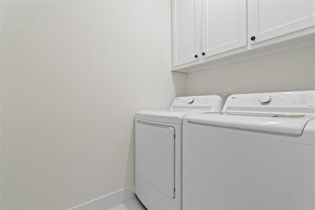 clothes washing area featuring washing machine and clothes dryer and cabinets