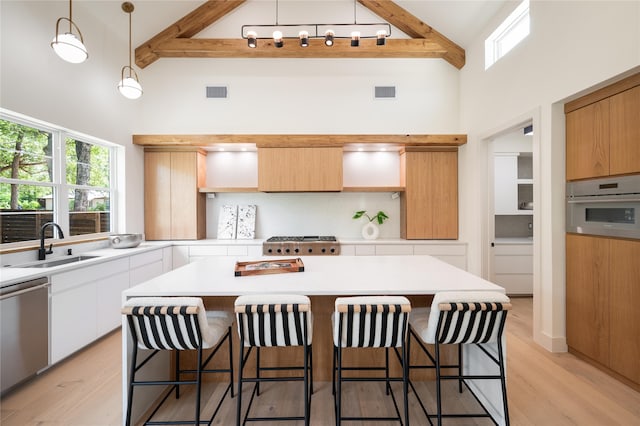 kitchen featuring appliances with stainless steel finishes, white cabinets, light hardwood / wood-style flooring, and decorative light fixtures