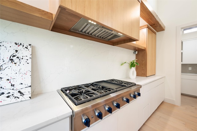 kitchen featuring white cabinetry, stainless steel gas cooktop, decorative backsplash, and light hardwood / wood-style flooring