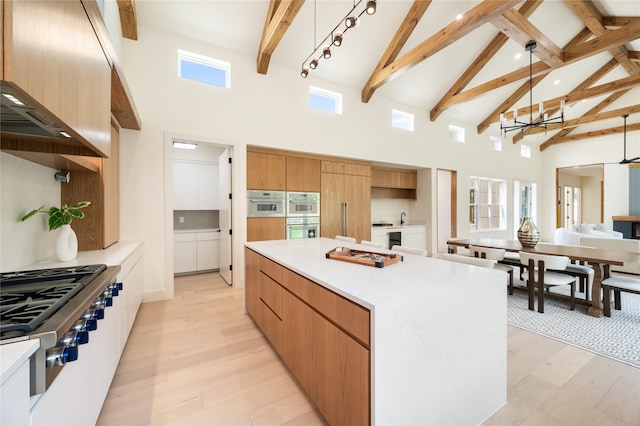 kitchen with beam ceiling, hanging light fixtures, high vaulted ceiling, light hardwood / wood-style floors, and a center island