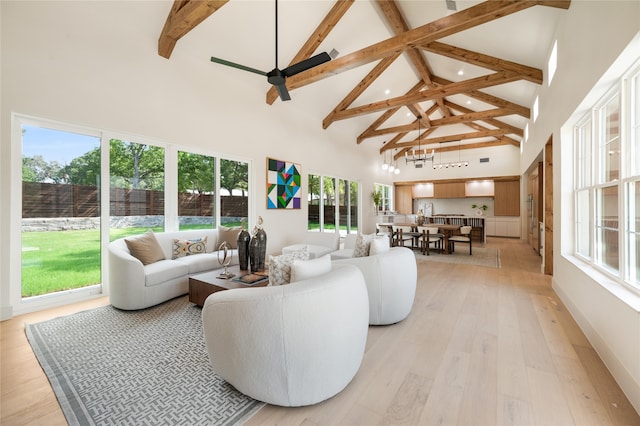 living room featuring beam ceiling, ceiling fan with notable chandelier, light wood-type flooring, and high vaulted ceiling