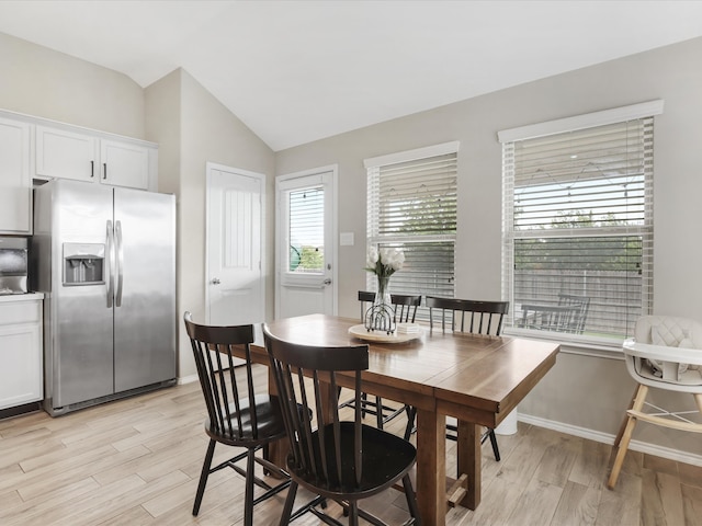 dining room with light wood-type flooring and vaulted ceiling