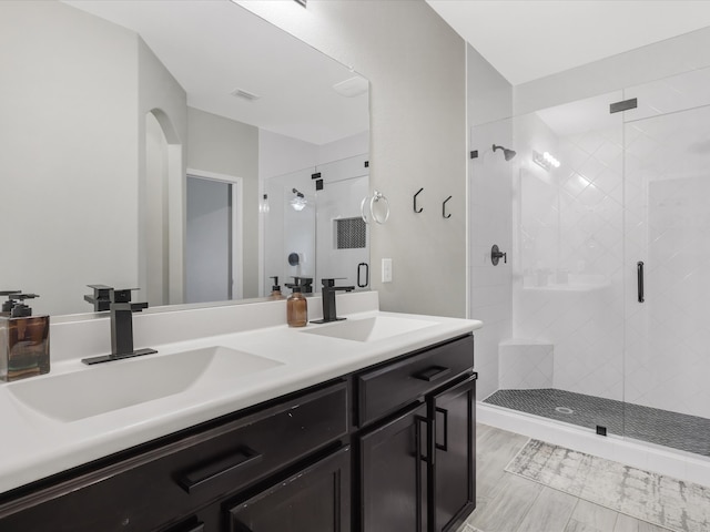 bathroom featuring a shower with door and vanity