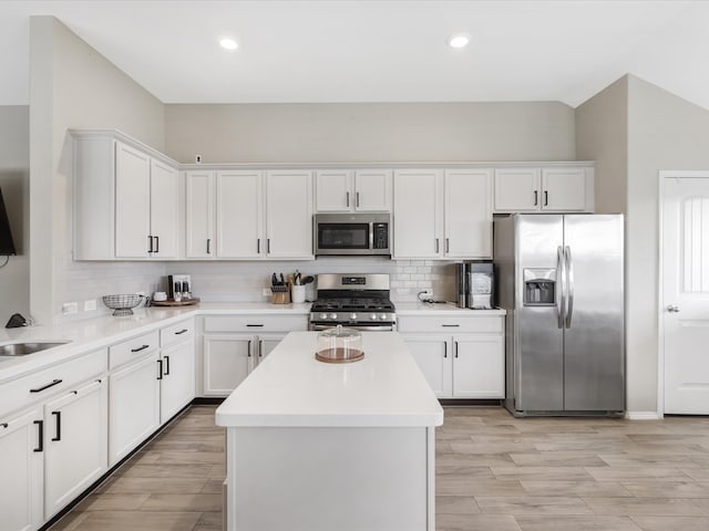 kitchen featuring a center island, stainless steel appliances, decorative backsplash, white cabinets, and light wood-type flooring