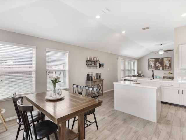 dining room with a wealth of natural light, sink, light hardwood / wood-style floors, and lofted ceiling