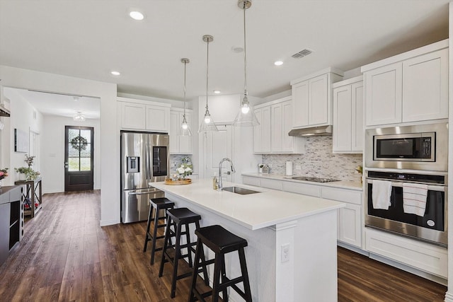 kitchen with white cabinetry, sink, hanging light fixtures, stainless steel appliances, and an island with sink