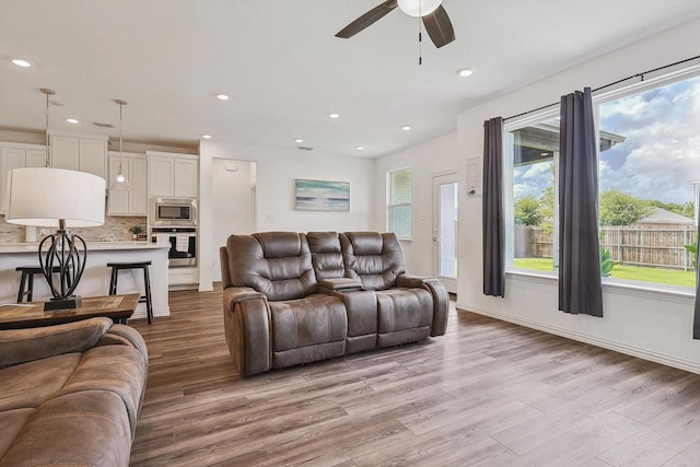 living room with ceiling fan and light hardwood / wood-style flooring