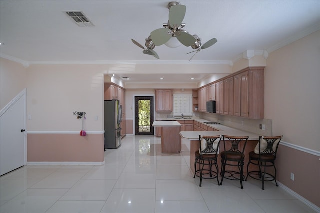 kitchen featuring stainless steel refrigerator, kitchen peninsula, a breakfast bar, and ornamental molding