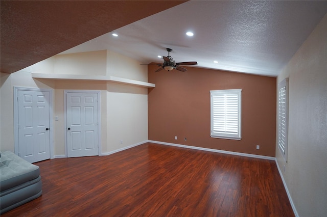 bonus room featuring a textured ceiling, vaulted ceiling, ceiling fan, and dark wood-type flooring