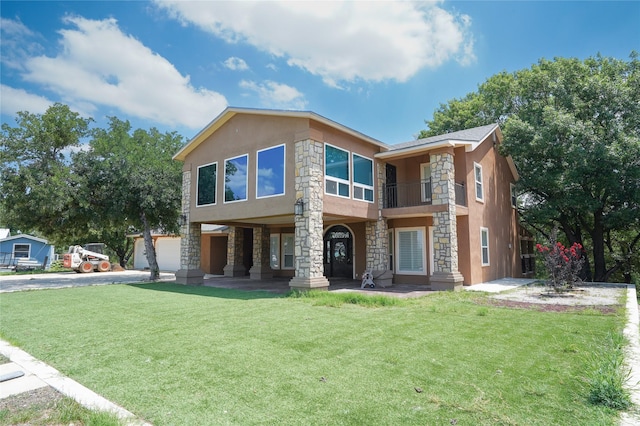 view of front facade with a balcony, a front lawn, and a garage