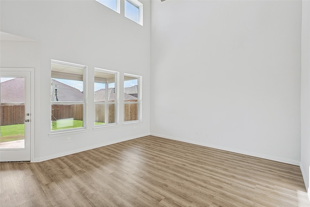 unfurnished living room featuring a towering ceiling and light wood-type flooring