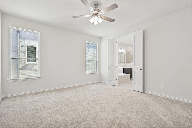 unfurnished bedroom with ceiling fan, light colored carpet, and ensuite bath