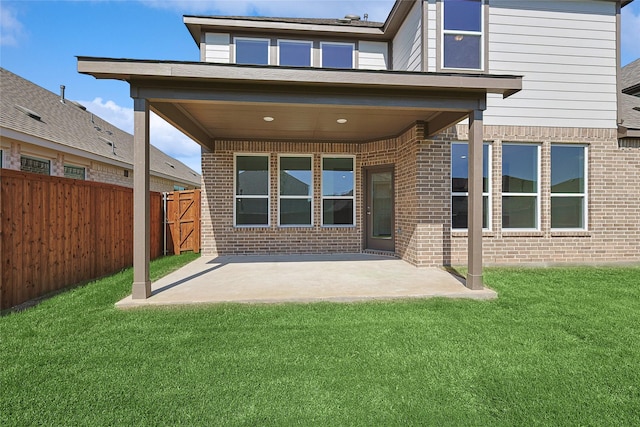 rear view of house featuring a lawn and a patio