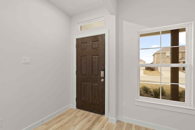 entrance foyer with a wealth of natural light, light wood-style flooring, and baseboards