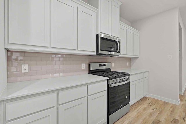 kitchen featuring light hardwood / wood-style flooring, appliances with stainless steel finishes, backsplash, light stone countertops, and white cabinets