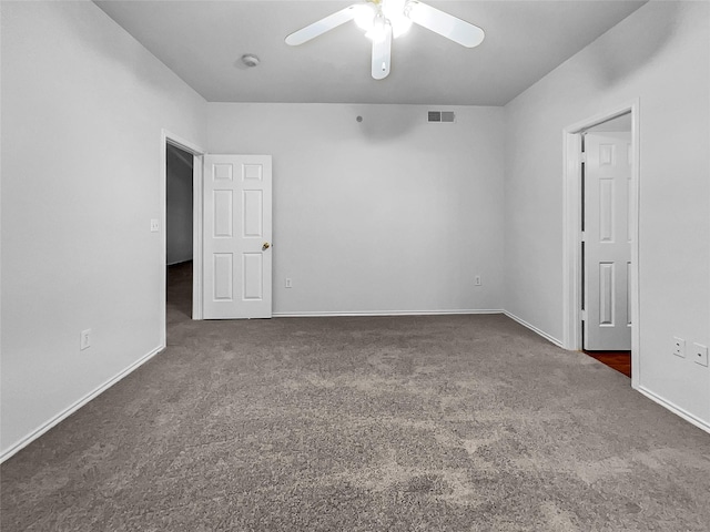 spare room featuring dark colored carpet and ceiling fan