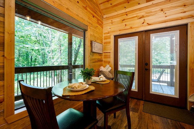 dining area featuring wood-type flooring, french doors, lofted ceiling, and wooden walls