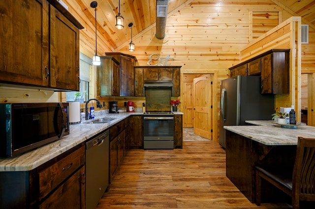 kitchen with wooden walls, stainless steel appliances, vaulted ceiling, and hardwood / wood-style flooring