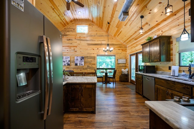 kitchen with stainless steel appliances, wood walls, hanging light fixtures, and dark hardwood / wood-style flooring