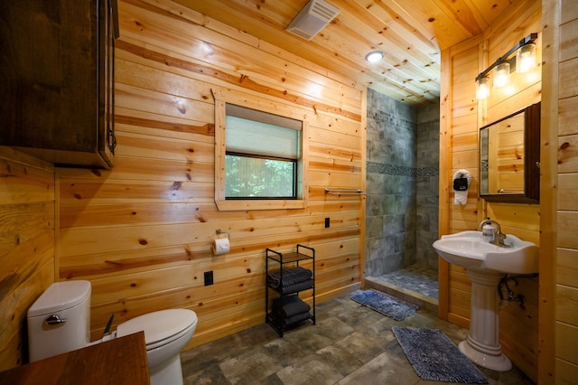 bathroom with tiled shower, wood ceiling, and wood walls