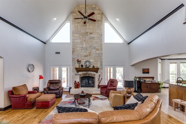 living room featuring ceiling fan, light hardwood / wood-style flooring, a fireplace, and french doors