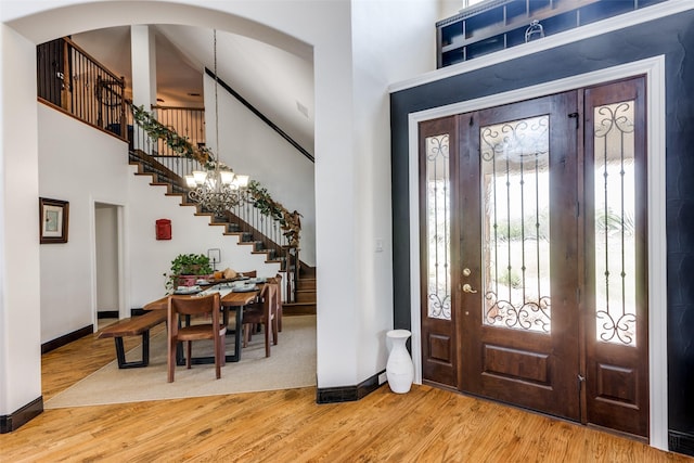 entrance foyer with hardwood / wood-style floors, a towering ceiling, and a notable chandelier