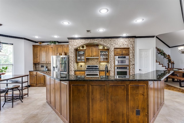 kitchen with a large island, decorative backsplash, stainless steel appliances, and light tile patterned flooring