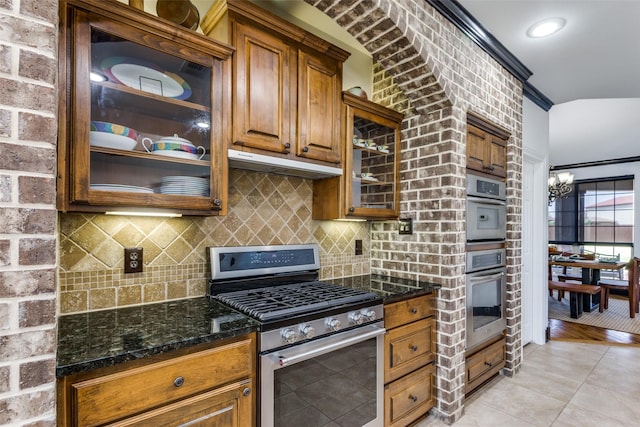 kitchen with tasteful backsplash, dark stone countertops, a chandelier, light tile patterned floors, and stainless steel appliances