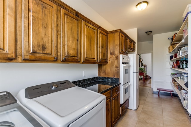 laundry area with cabinets, washing machine and dryer, and light tile patterned floors