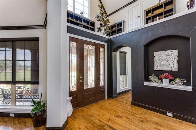 entryway featuring hardwood / wood-style flooring, a towering ceiling, and crown molding