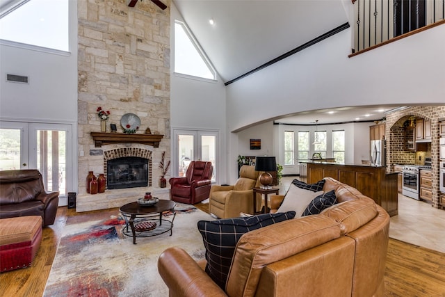 living room featuring a stone fireplace, light hardwood / wood-style floors, and french doors