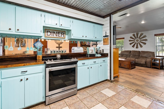 kitchen with wood counters, light hardwood / wood-style floors, stainless steel range oven, and blue cabinets