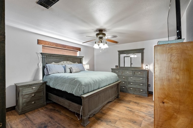 bedroom with ceiling fan, wood-type flooring, and a textured ceiling