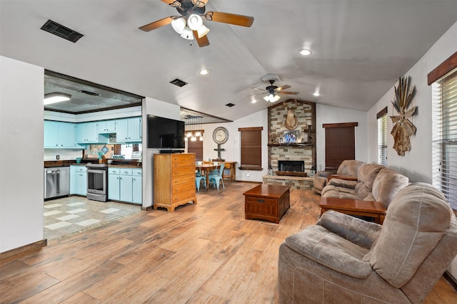 living room with lofted ceiling, ceiling fan, light wood-type flooring, and a fireplace