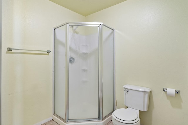 bathroom featuring a shower with shower door and toilet