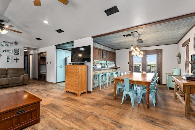 dining room with hardwood / wood-style floors, ceiling fan with notable chandelier, french doors, and lofted ceiling