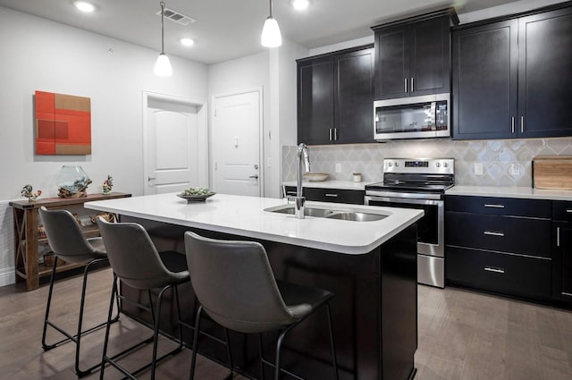 kitchen with a breakfast bar area, sink, a center island with sink, and appliances with stainless steel finishes