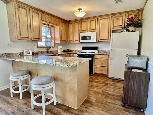 kitchen with light stone countertops, white appliances, dark wood-type flooring, sink, and kitchen peninsula