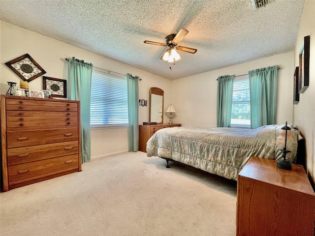 bedroom with a textured ceiling, ceiling fan, and light colored carpet