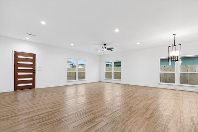 unfurnished living room featuring ceiling fan with notable chandelier and light hardwood / wood-style floors