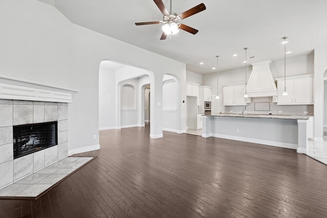 unfurnished living room with ceiling fan, a fireplace, dark hardwood / wood-style flooring, and sink