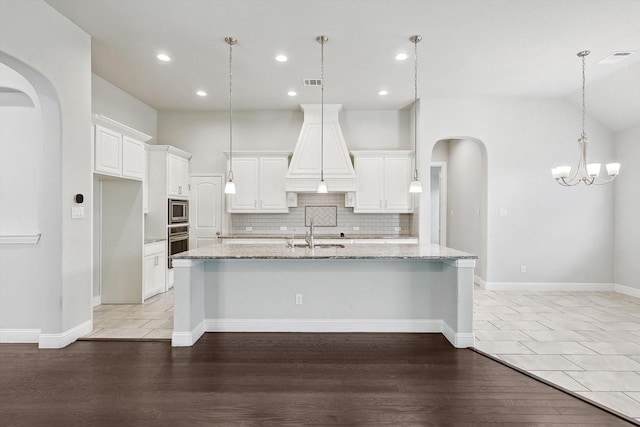 kitchen with decorative light fixtures, white cabinets, a large island, light stone counters, and stainless steel appliances